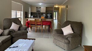 A living room with two sofas, a coffee table, and a dining area with a red tablecloth. - Whole House with 4 Queen Beds - Closer to Melbourne Airport - 8 Guests (Kurunjang)