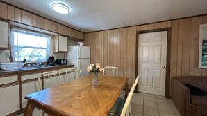 Una cocina con paneles de madera, una mesa de comedor, sillas, un refrigerador y una ventana.