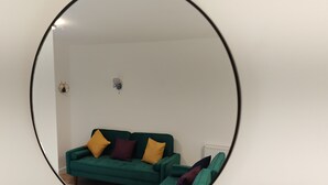 A green sofa with three cushions in a room with white walls and a radiator. - Charming 5 Bedroom House in Bexley (Bexley)
