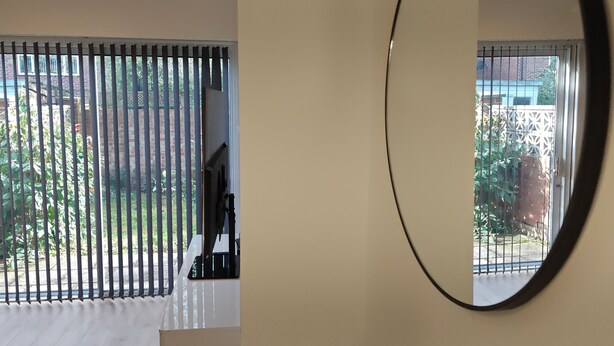 A room with a large window, a mirror, and a view of a garden. - Charming 5 Bedroom House in Bexley (Bexley)