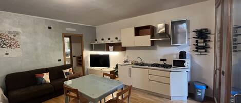 A compact living space with a dining area, kitchenette, and a sofa.