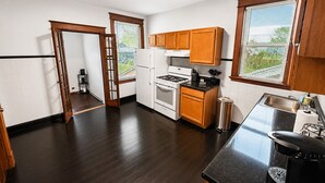 Una cocina moderna con suelo de madera oscura, armarios blancos, una estufa y un fregadero.