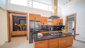 Una cocina moderna con armarios de madera, un refrigerador de acero inoxidable y una isla central.