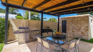 Un patio al aire libre con una parrilla, zona de estar y un muro de piedra.