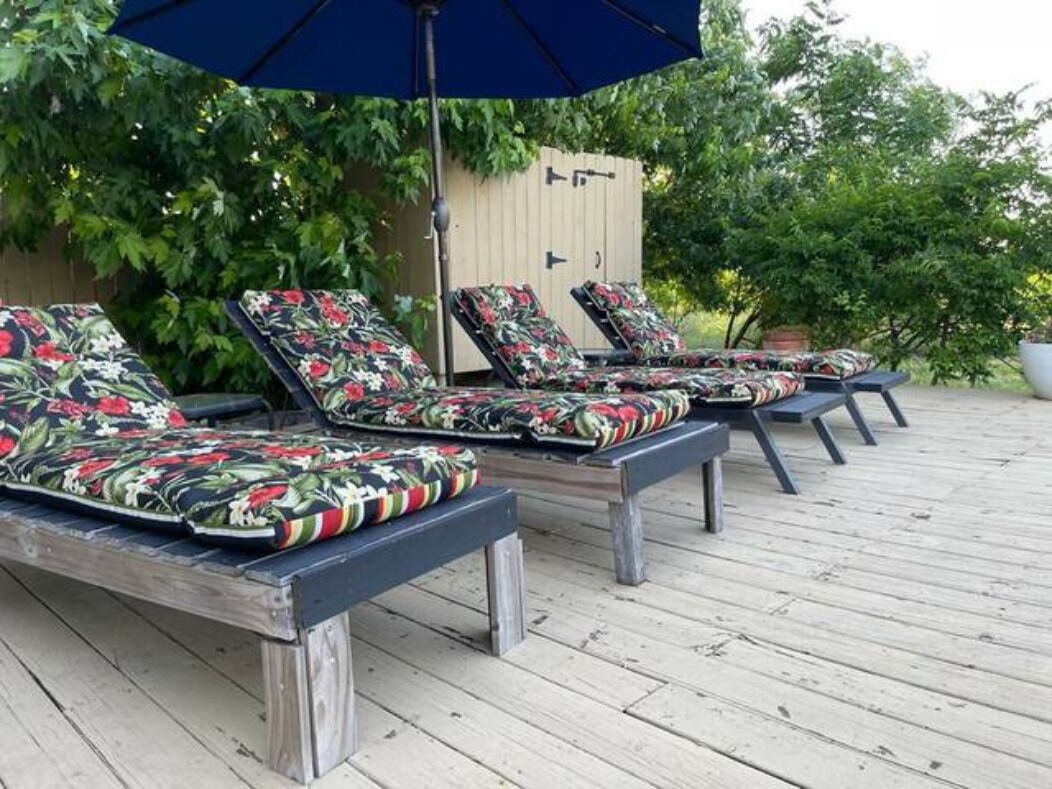 A deck with lounge chairs and a wooden structure in the background.