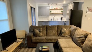 A modern living room with a sectional sofa, a flat-screen TV, and a coffee table. - Kennedy’s Camelot, a walkable family condo in beautiful Angel Fire! (Angel Fire)