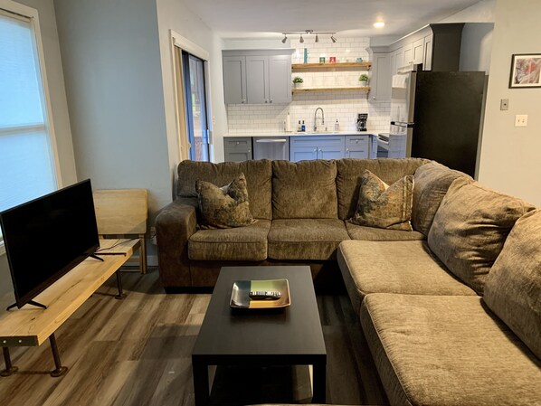 A modern living room with a sectional sofa, a flat-screen TV, and a coffee table. - Kennedy’s Camelot, a walkable family condo in beautiful Angel Fire! (Angel Fire)
