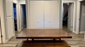 A room with a large wooden table in the center, white double doors, and a ceiling light fixture. - Kennedy’s Camelot, a walkable family condo in beautiful Angel Fire! (Angel Fire)