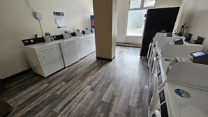 A laundry facility with multiple washing machines and dryers, a wooden floor, and a window providing natural light. - Pet Friendly King Studio, Center Village, walk to slopes 446 (Copper Mountain)