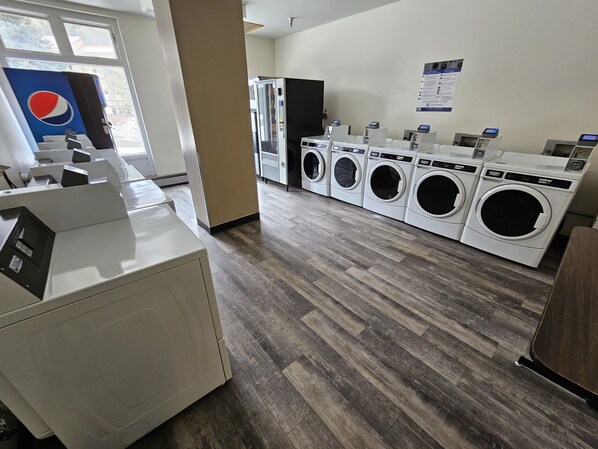 A laundry facility with multiple washing machines, a vending machine, and a Pepsi refrigerator.