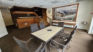 A conference room with a wooden staircase, a large painting of a snowy mountain landscape, and a clock on the wall. - Pet Friendly King Studio, Center Village, walk to slopes 446 (Copper Mountain)