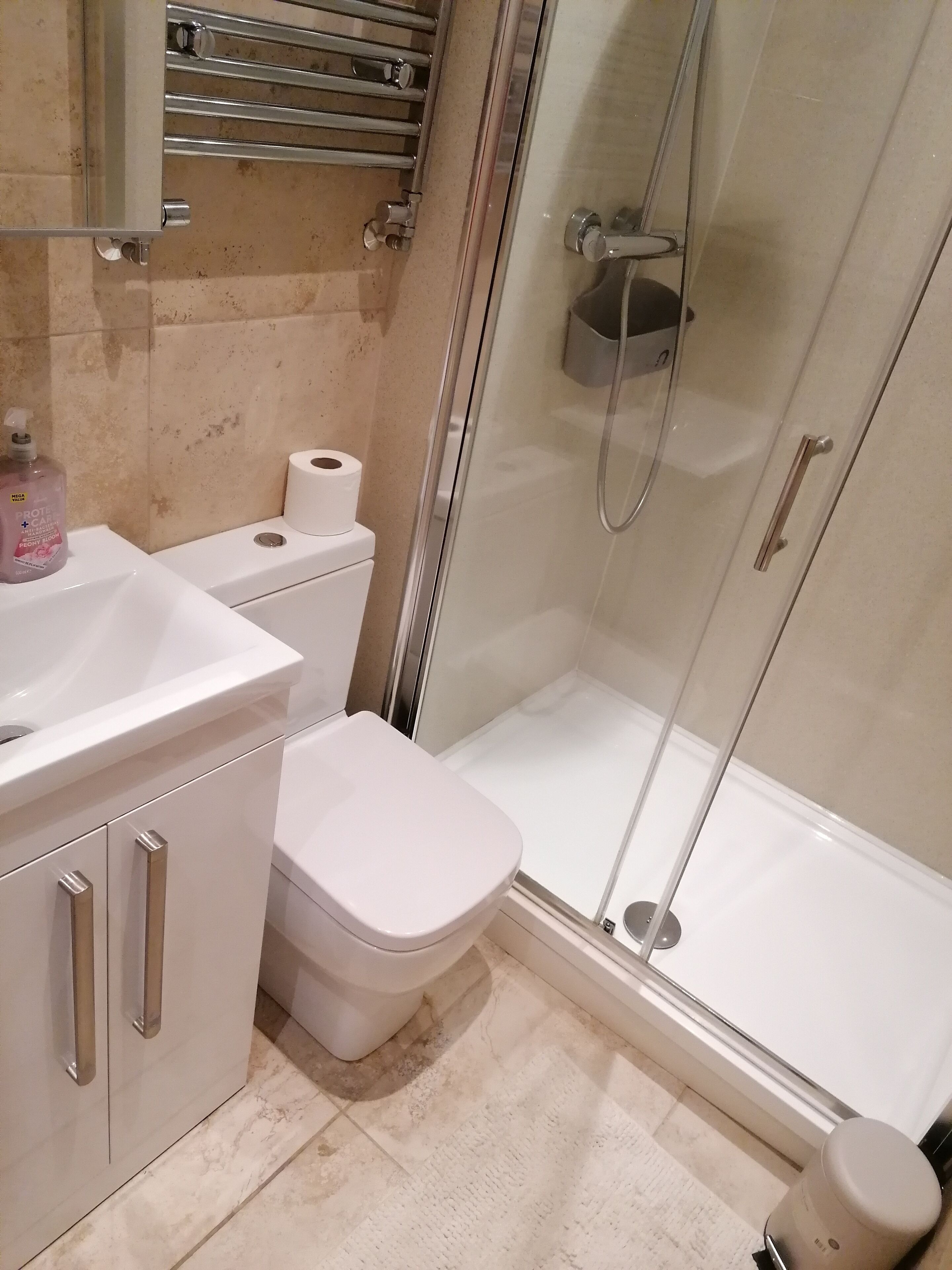 Un baño con inodoro, lavamanos y cabina de ducha de vidrio.