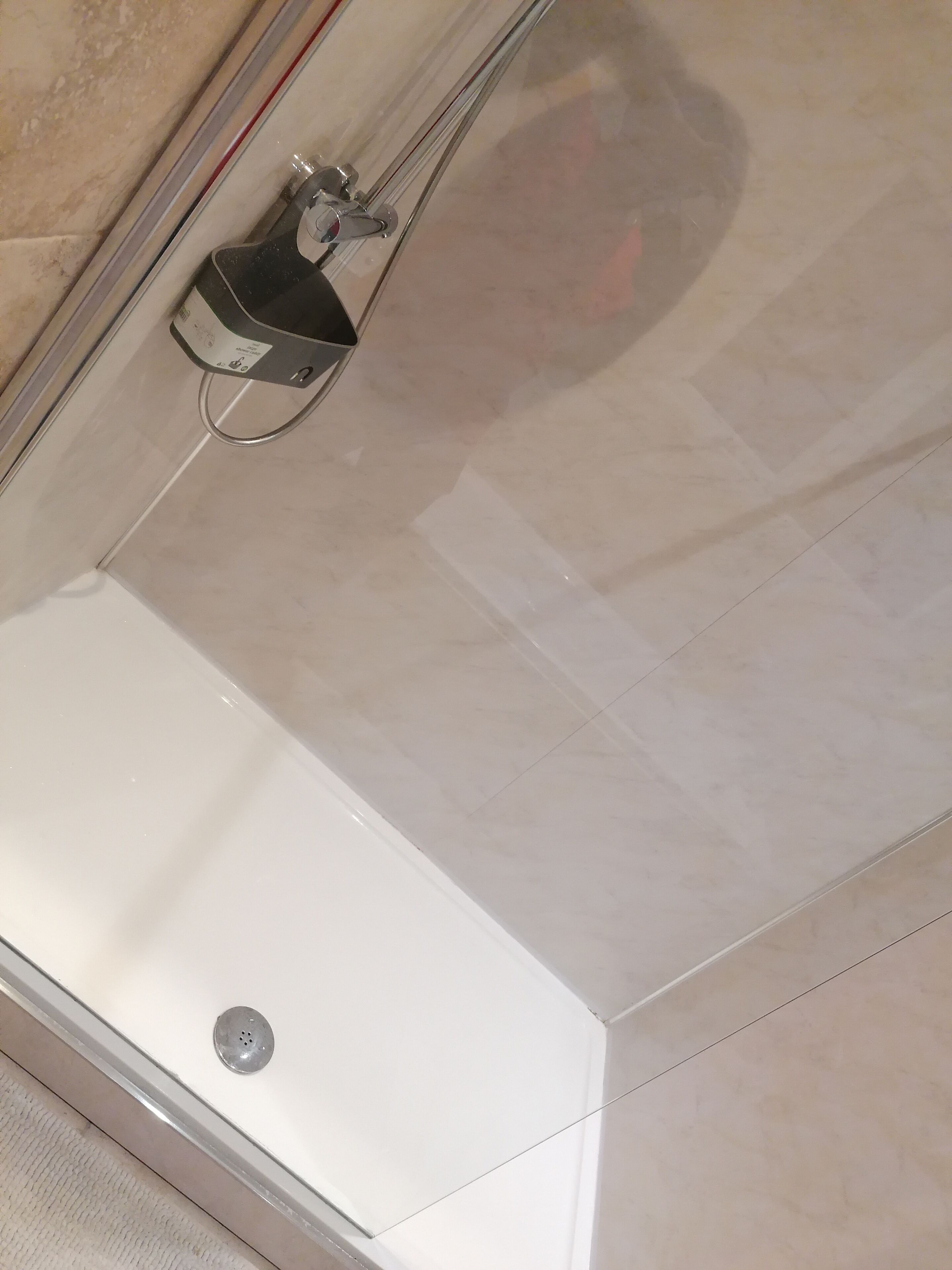 Een moderne badkamer met een witte badkuip, een handdouche en een zichtbare afvoer.