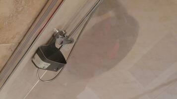 Un baño moderno con una bañera blanca, un cabezal de ducha de mano y desagüe visible.