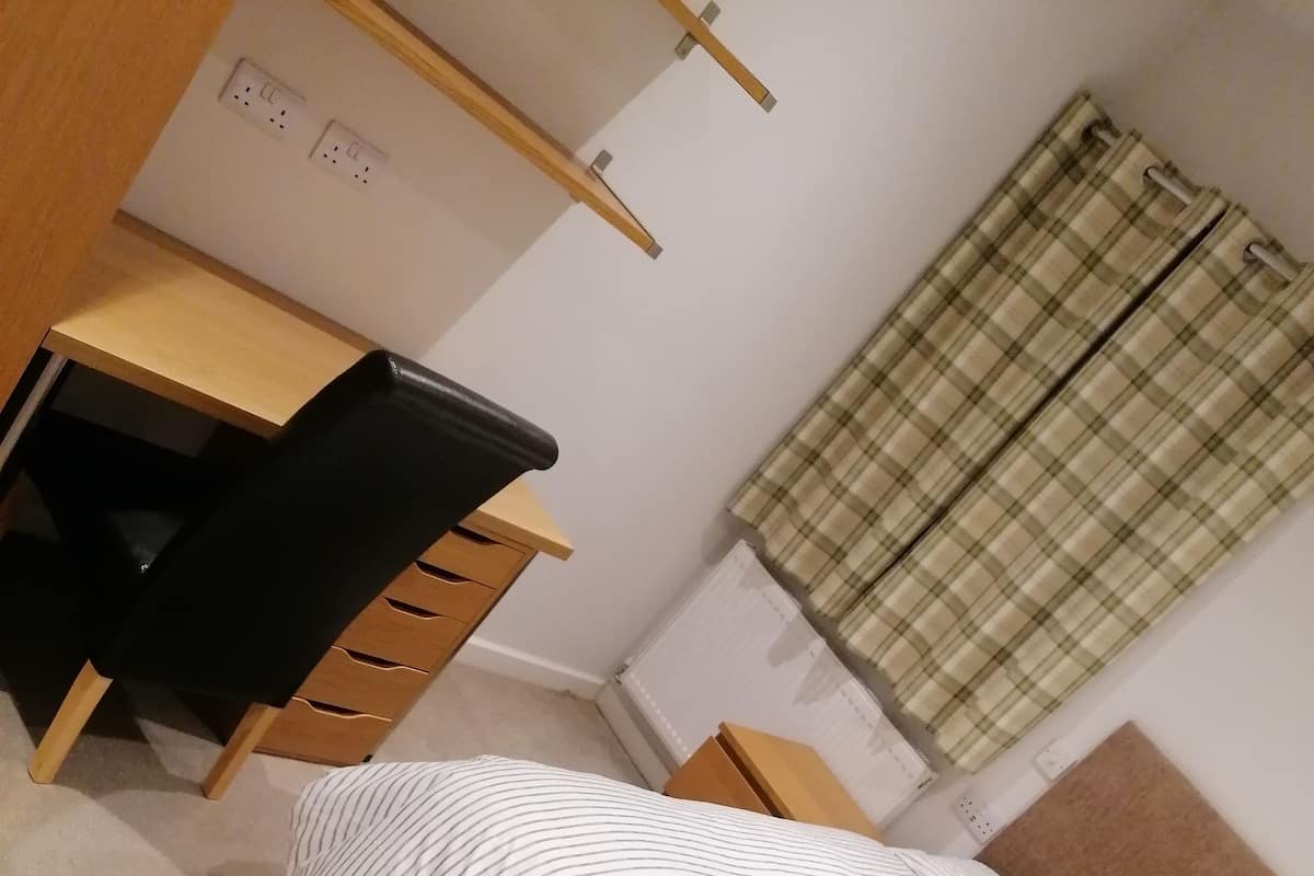 Et soveværelse med seng, skrivebord og stol.