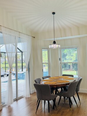A dining area with a wooden table, grey chairs, and a hanging chandelier. - Beautiful welcoming house in Paradise named Naples! (Naples)