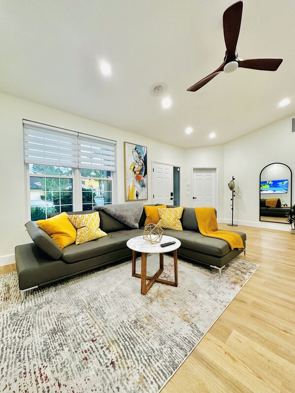 A modern living room with a sectional sofa, a coffee table, and a ceiling fan.