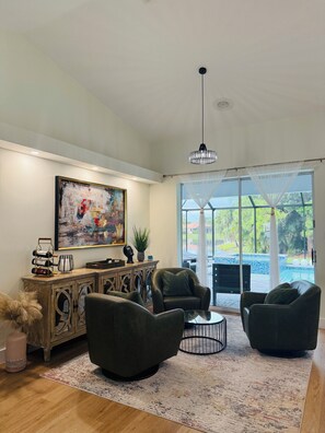 A spacious living room with a large painting, a wooden cabinet, and comfortable seating. - Beautiful welcoming house in Paradise named Naples! (Naples)