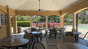An outdoor patio with round tables and chairs, a ceiling fan, and a sign warning about swimming. - Amazing Centrally Located Home in Peaceful Area (Jacksonville)
