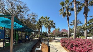 A playground with a blue canopy, palm trees, and a pathway lined with benches. - Amazing Centrally Located Home in Peaceful Area (Jacksonville)