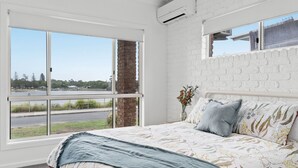 Ein Schlafzimmer mit großem Fenster, einer Ziegelwand und einem Bett mit blumigem Bettbezug.