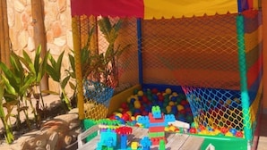 A wooden table with chairs in front of a play area with a ball pit and a climbing net. - Pousada Deu Praia Maragogi  (Maragogi)