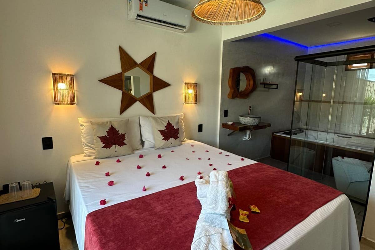 A hotel room with a large bed, a star-shaped mirror, wall sconces, and a kitchenette.