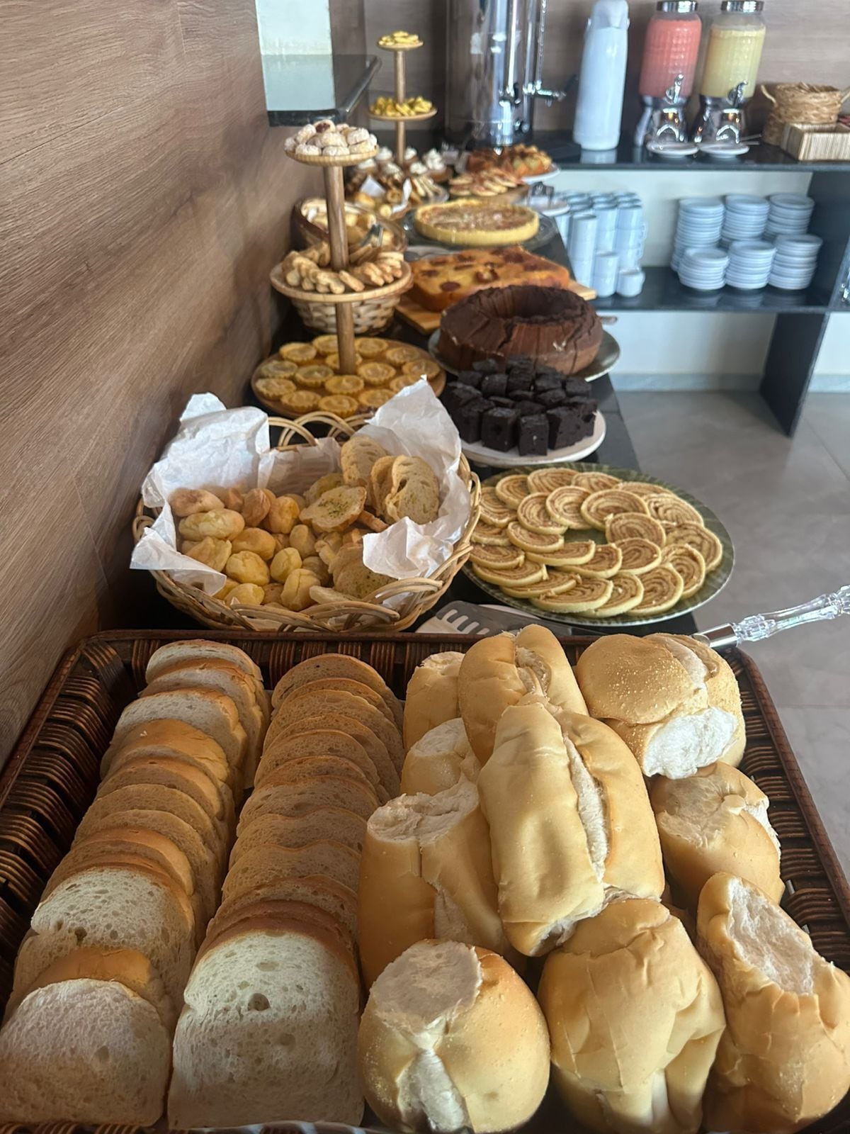 A buffet with various breads, pastries, and desserts.