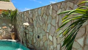 A swimming pool with a stone wall and a small waterfall feature. - Pousada Deu Praia Maragogi  (Maragogi)