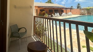 A balcony with a pool, a chair, and a table. - Pousada Deu Praia Maragogi  (Maragogi)