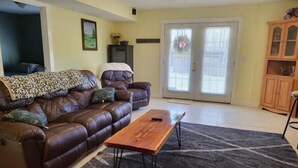 A living room with a brown leather sofa, a wooden coffee table, and a patterned rug. - Bear Mountain Farm 2.0 (Monroe)