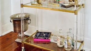 Ein Glastisch mit goldfarbenem Rahmen, Büchern und Flaschen.
