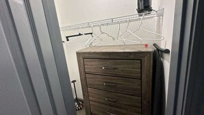 Ein Zimmer mit einem Holzkleiderschrank, einem Wäscheständer aus Metall und einem Staubsauger.