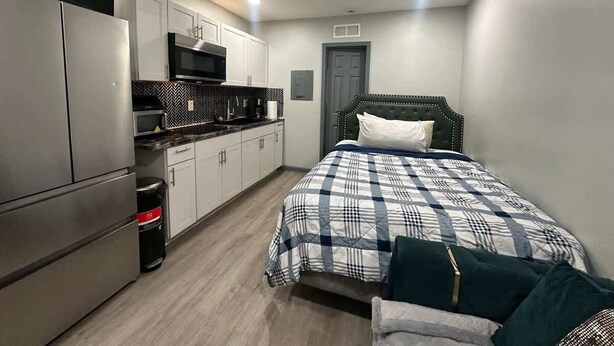 Ein gemütliches Schlafzimmer mit Bett, Deckenventilator, Küchenzeile und einer Tür.