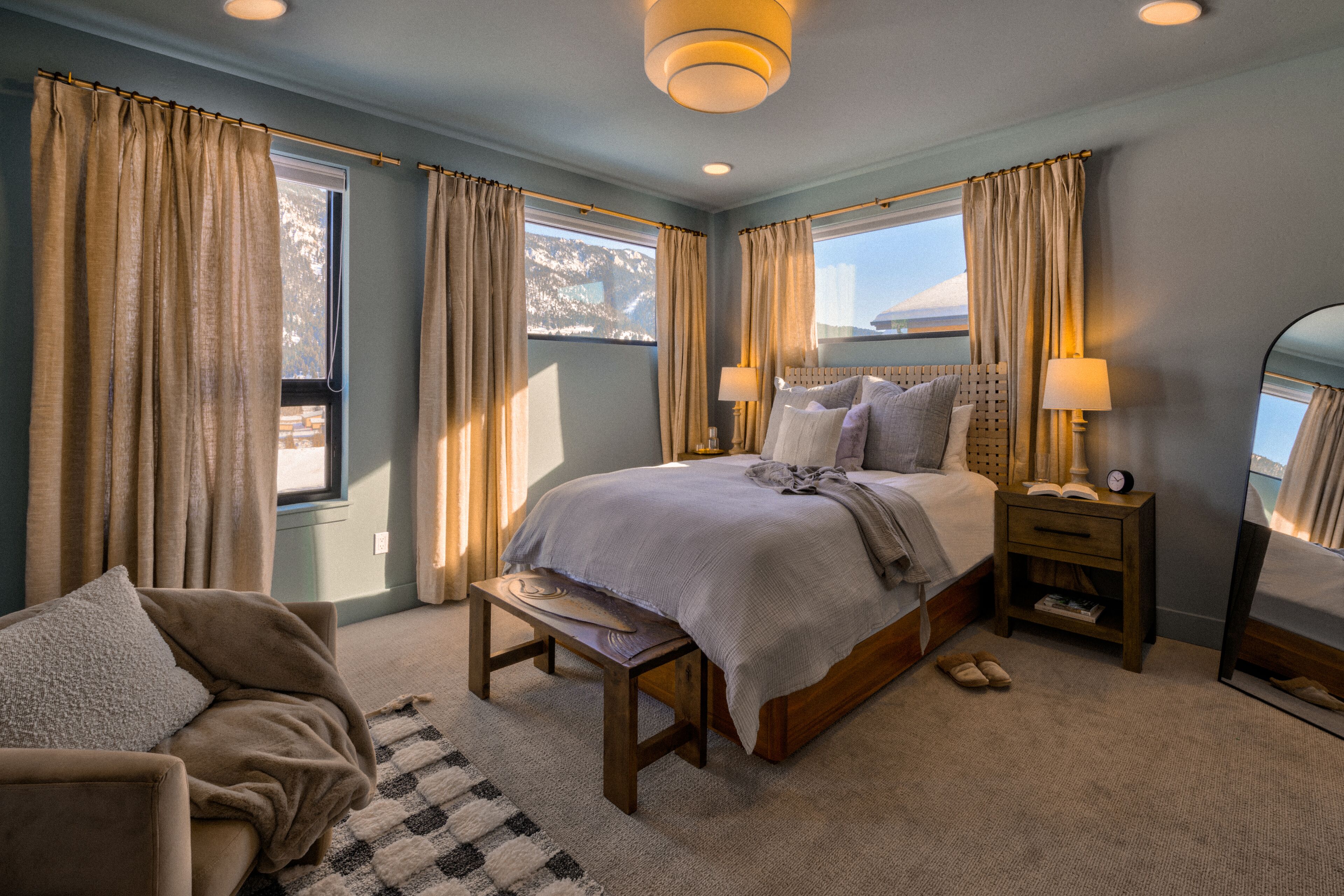 A bedroom with a large bed, bedside tables, a chair, and a view of the outdoors.