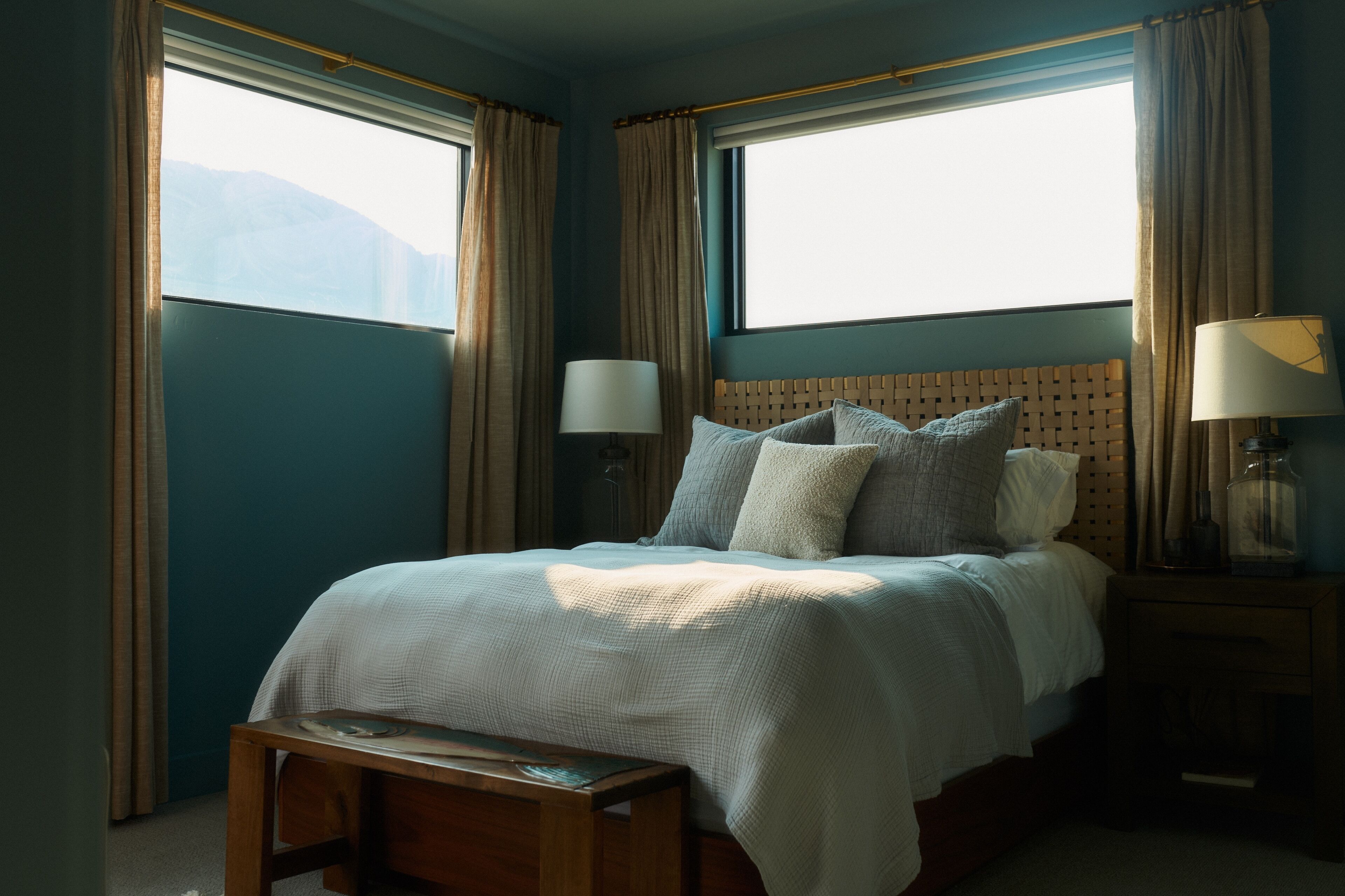 Ein Schlafzimmer mit einem großen Bett, zwei Nachttischlampen, einem Holzkopfende und einer Bank am Fußende.