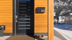Een houten gebouw met een zwarte deur en een bordje met het nummer 60.