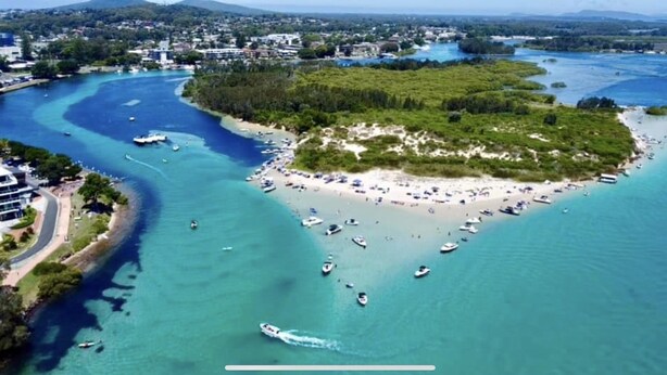 An aerial view of a coastal area with a beach, boats, and buildings. - Water views in town centre. Secure parking with lift. (Forster)