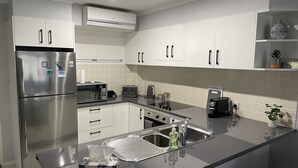A modern kitchen with stainless steel appliances, white cabinetry, and a black countertop. - Water views in town centre. Secure parking with lift. (Forster)