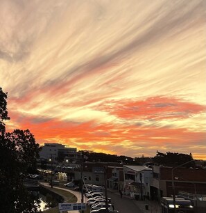 A sunset over a small town with buildings and parked cars. - Water views in town centre. Secure parking with lift. (Forster)