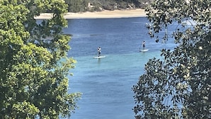 A coastal view with a beach, paddleboarders, and a dock with boats. - Water views in town centre. Secure parking with lift. (Forster)