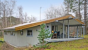 A small cabin with a porch and a covered outdoor seating area.