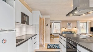 A modern kitchen with white cabinetry, a built-in oven, and a large island with a sink.