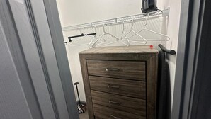 A bathroom with a wooden cabinet, a towel rack, and a hairdryer on a wall-mounted shelf.