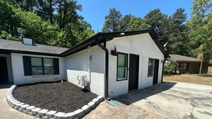 A single-story house with a front yard, a driveway, and a small garden area.