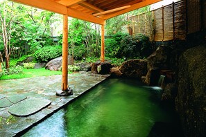 A stone pathway leading to a water feature in a garden with bamboo and greenery. - Hotel Plaza Geihinn (Yokote)