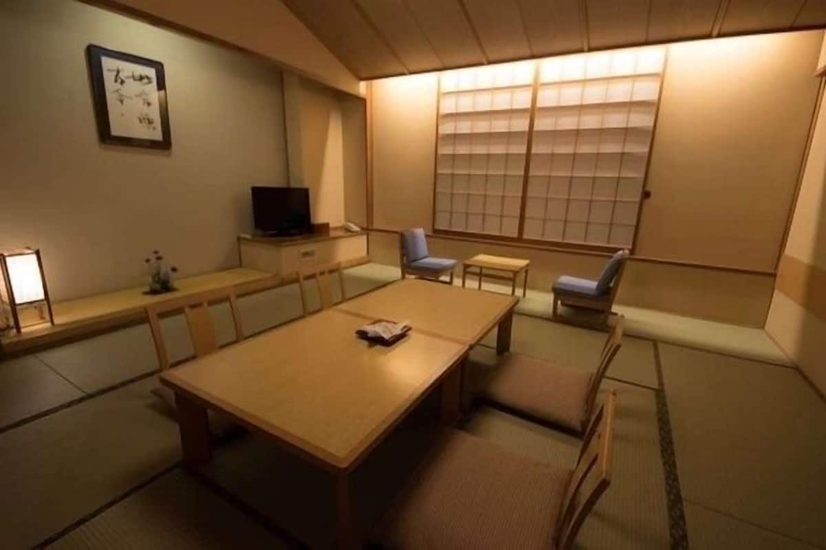 A traditional Japanese-style room with tatami flooring, a low table, and a television on a cabinet.