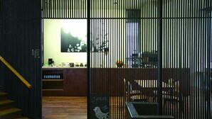 Interior de un restaurante con piso de madera, una barra con cartelera y una vista a través de un panel vertical.