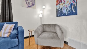 A living room with a blue sofa, a grey armchair, a small round table, and a floor lamp. - Fun & Funky #2 centrally located in Memphis! (Memphis)