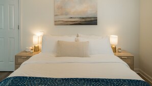 A neatly made bed with white linens and a blue patterned throw, flanked by two bedside tables with lamps, one of which has a jar on it. - Riverview Retreat at The Wanderer  (Boone)